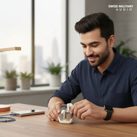 Swiss Military Audio white wireless earbuds with chrome accents and a charging case featuring a rainbow LED indicator.